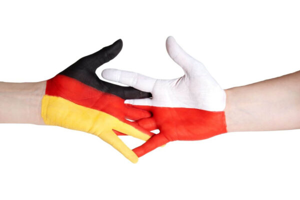 Dwie dłonie pomalowane w barwy flag Niemiec i Polski, symbolizujące współpracę, co przypomina mi o pracy tłumacza niemieckiego.