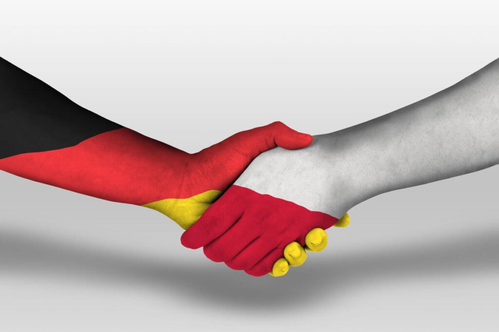 Uścisk dłoni w barwach niemieckiej i polskiej flagi symbolizuje współpracę, jaką często wspiera tłumacz przysięgły niemiecki.